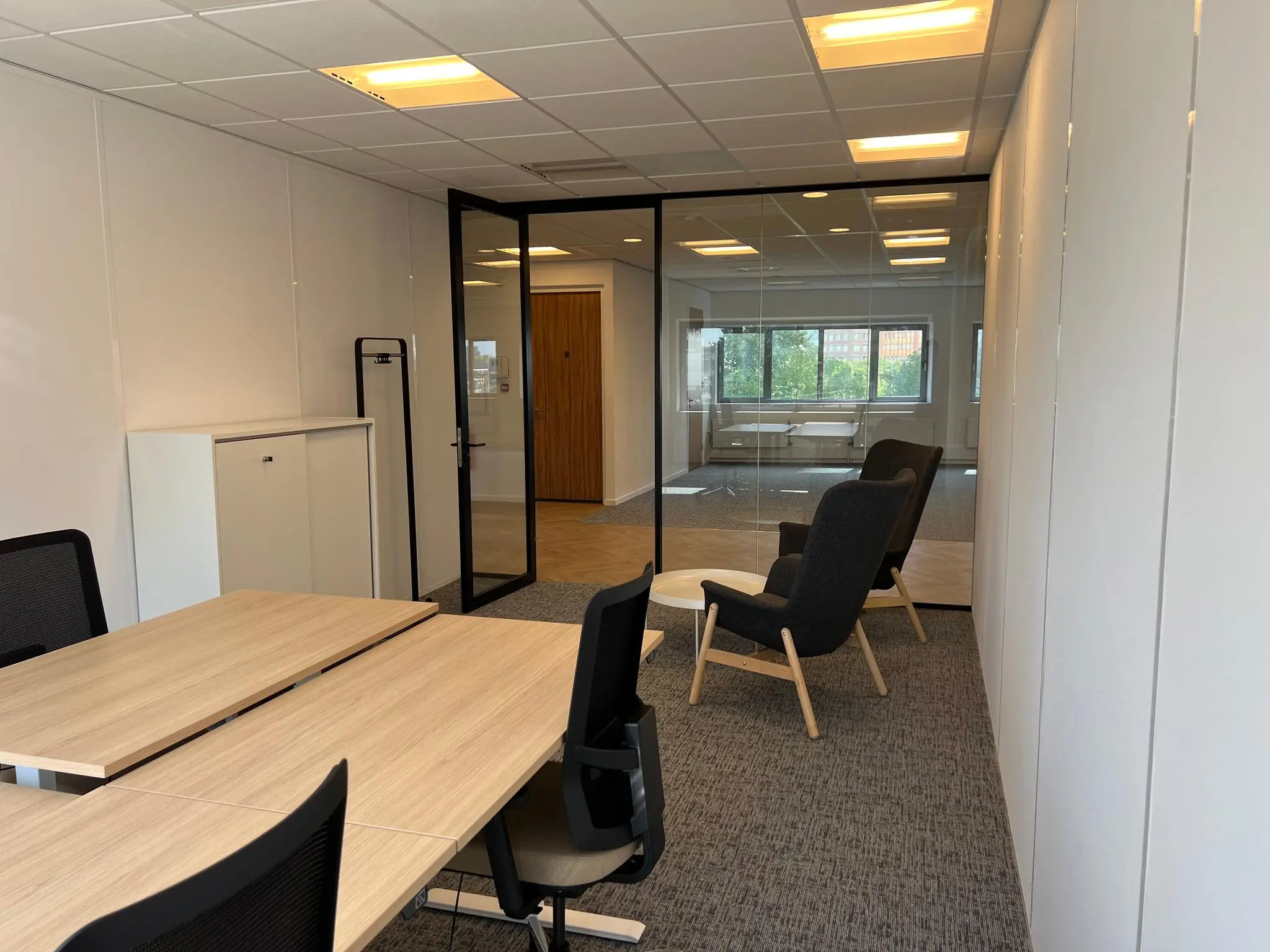 Modern kantoorinterieur in Rivium Quadrant met werkplekken, zithoek en glazen vergaderruimte.